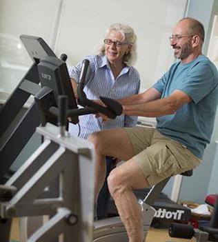 Patient on stationary bike while therapist observes
